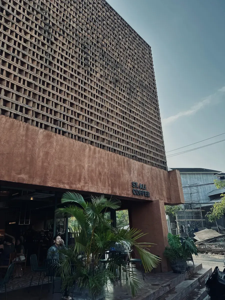 Wide view of the terracotta lattice facade and recessed outdoor seating along the Pererenan corner