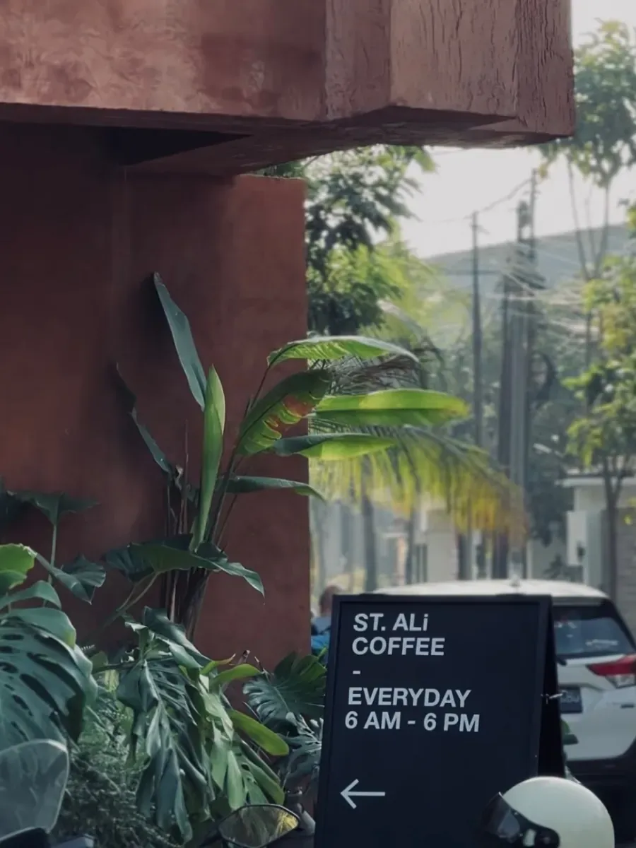 A-frame chalkboard on the sidewalk reading ST. ALi Coffee, everyday 6 AM to 6 PM, with an arrow toward the entrance