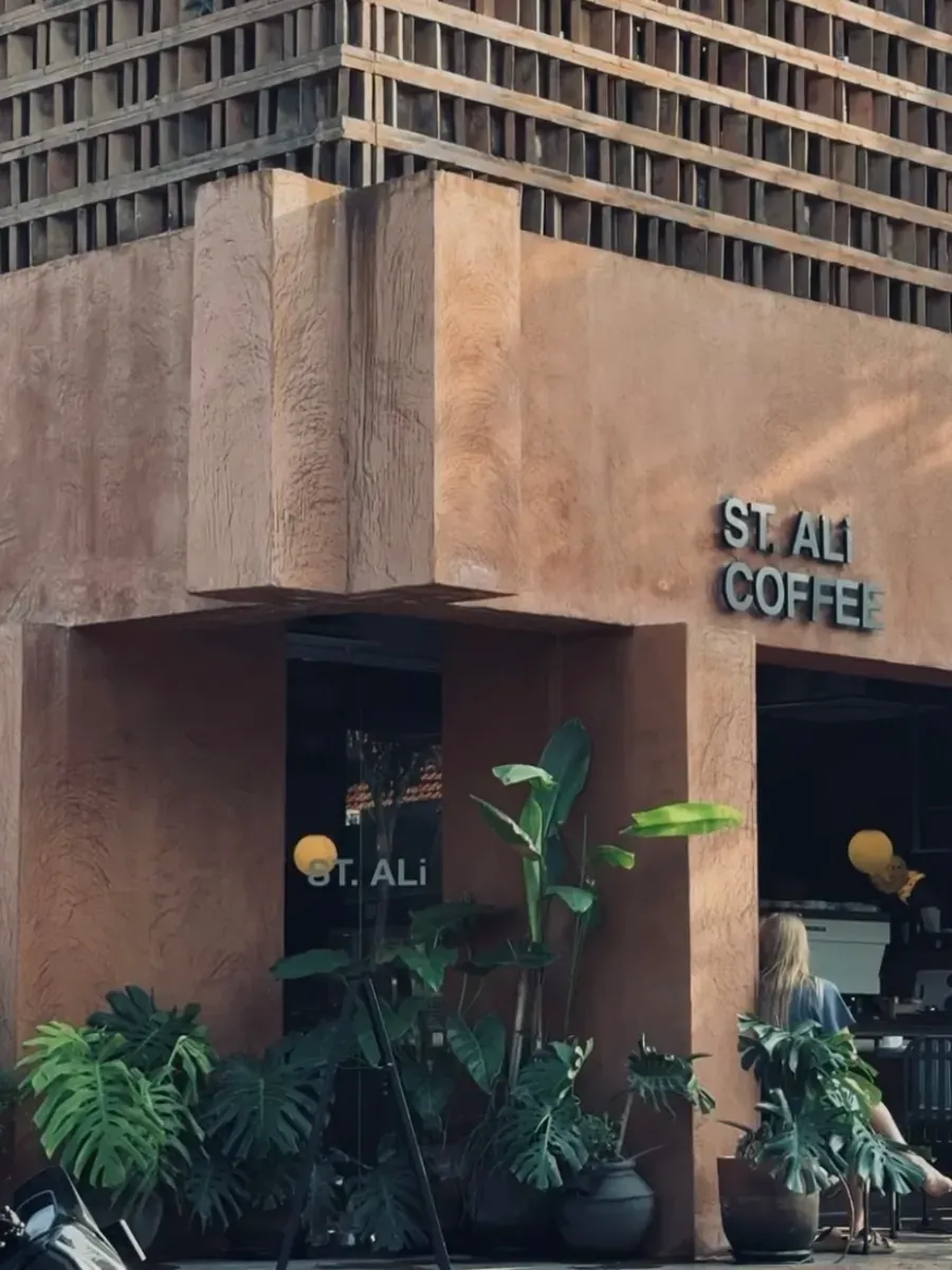 Terracotta corner pillar and ST. ALi Coffee lettering, with monstera pots and outdoor seating beyond