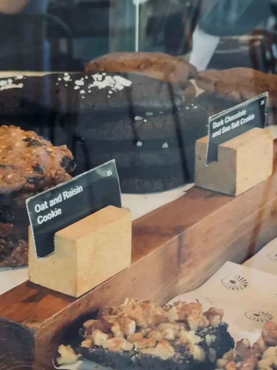 Pastry case with oat and raisin cookies and dark chocolate sea salt cookies on parchment