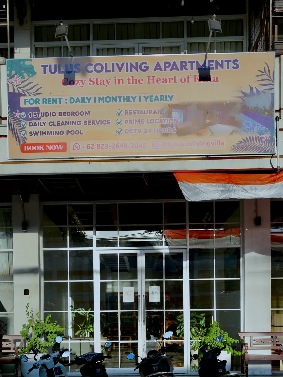 Tulus Coliving Apartments storefront sign above glass doors with scooters parked in front