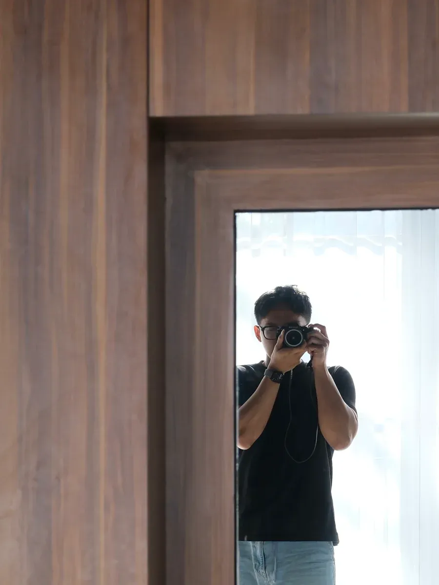 Mirror selfie in the wooden wardrobe, reflecting the bright room behind the photographer