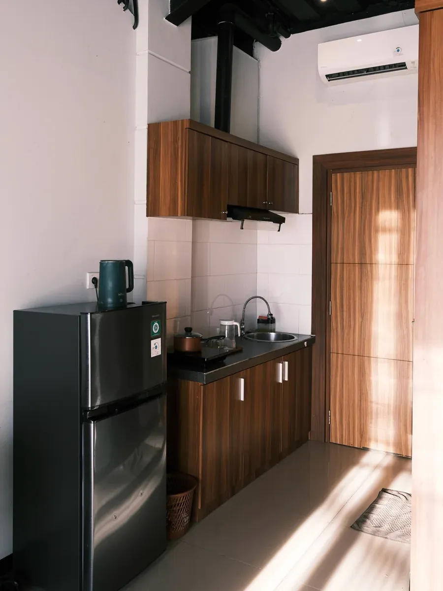 Compact kitchenette with wood cabinets, induction cooktop, sink, fridge, and kettle