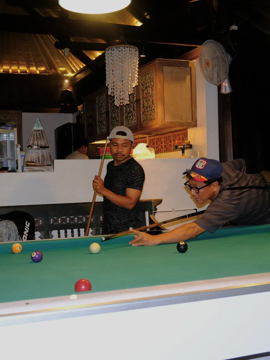 Two guests playing billiards in the common room at night