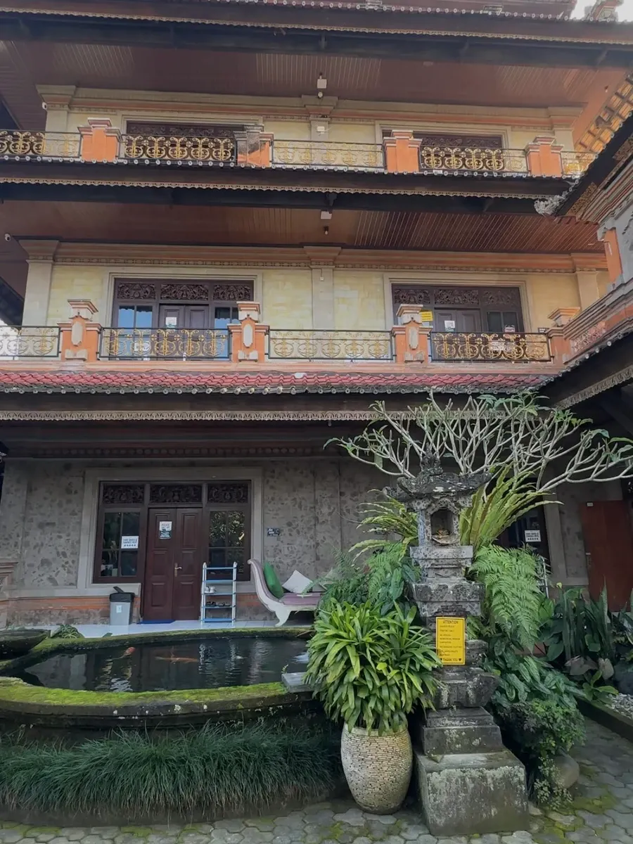 The hostel courtyard facade with a mossy koi pond and shrine