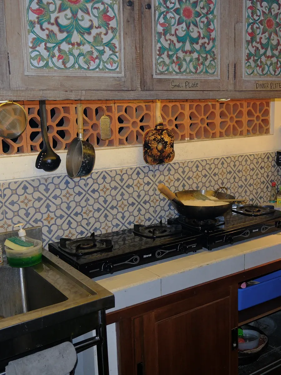 The shared kitchen at night, with a wok on portable gas burners and patterned tile