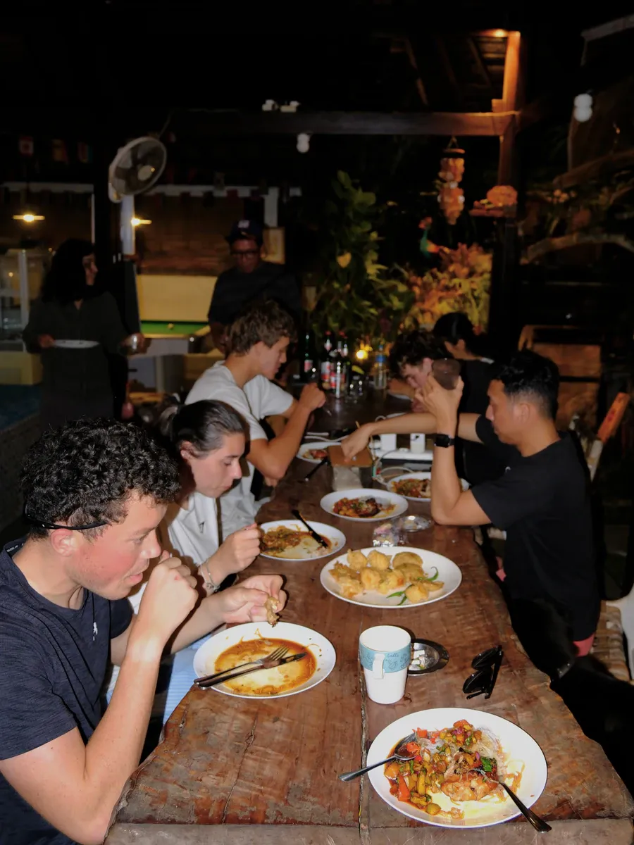 Guests eating together at a long wooden communal table