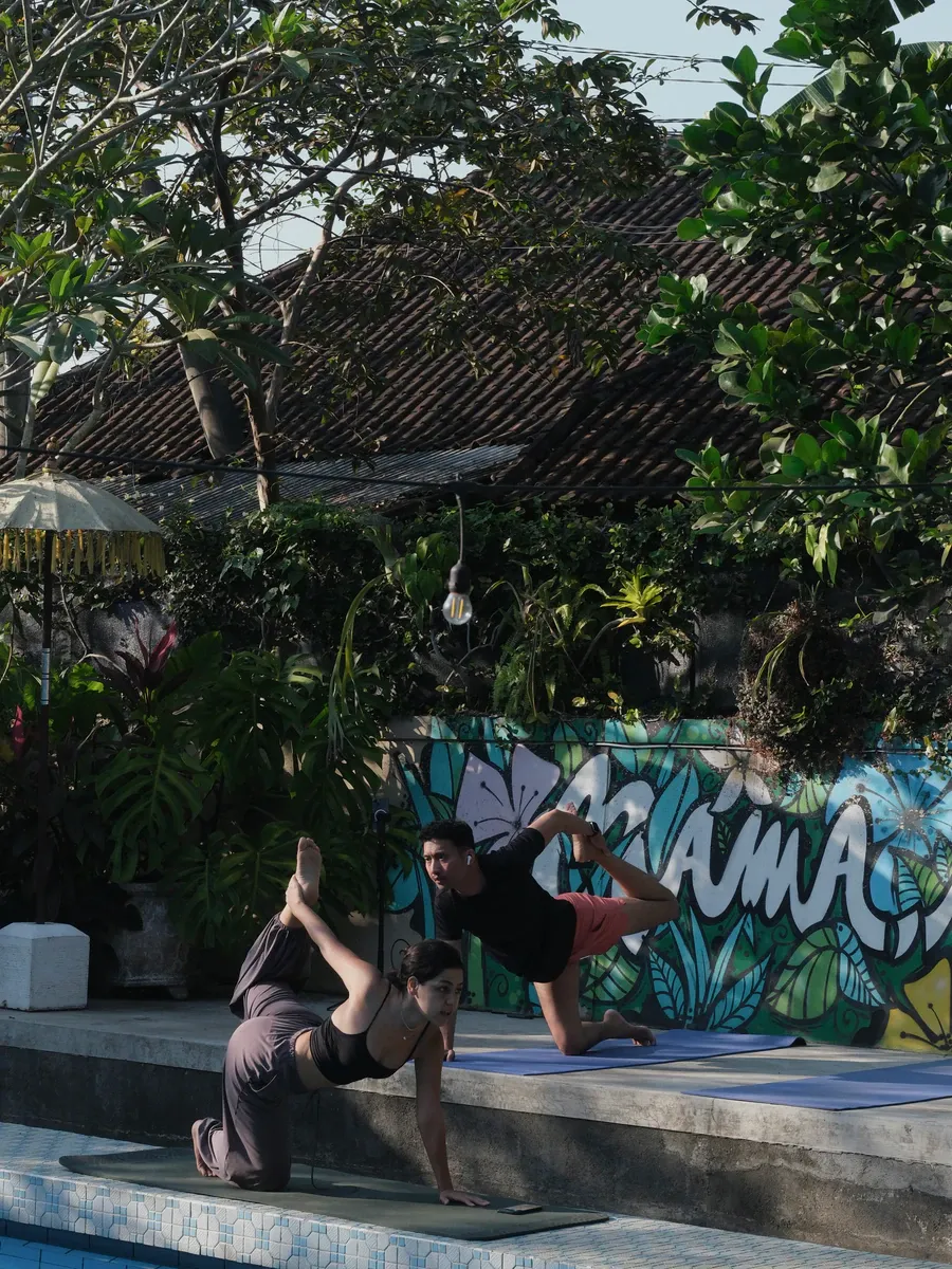 Two people in a yoga pose by the pool mural