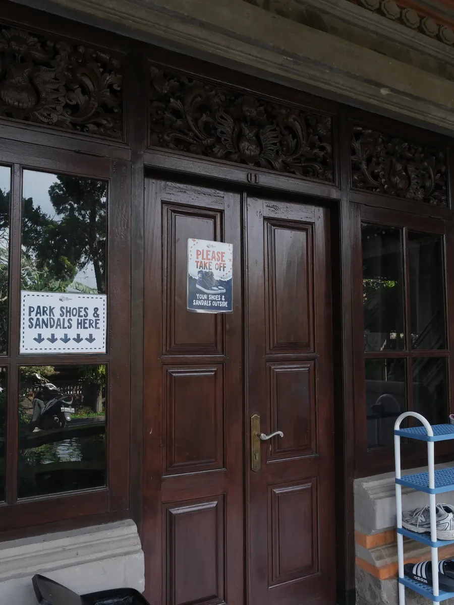 Carved wooden doors with signs asking guests to take off their shoes